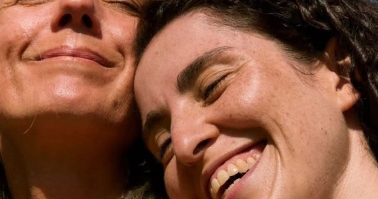 Two women hugging, smiling in the sun